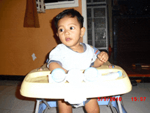 a baby is sitting in a high chair with the date 5/9/2010 on the bottom