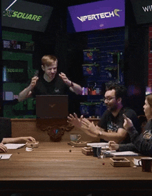 a group of people are sitting around a table with a vipertech sign above them