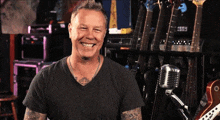 a man with a tattoo on his chest is smiling in front of a microphone