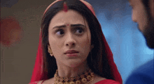 a woman in a red sari is looking at a man in a blue jacket .