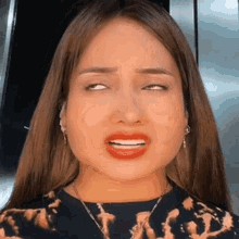 a woman with long hair is making a funny face with her eyes closed .