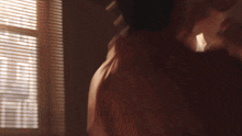a man and woman are kissing in front of a window .