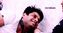 a man is smiling while laying on a bed with a woman .