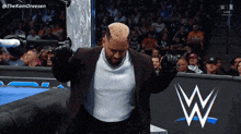 a man in a suit is standing in front of a wwe sign