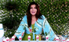 a woman in a blue and green floral shirt is sitting at a table