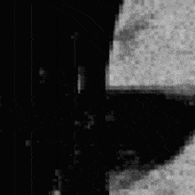 a black and white photo of a person 's face with a red eye and a black background .
