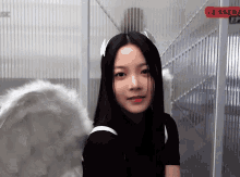 a woman wearing angel wings and horns stands in front of a glass wall that says le scena