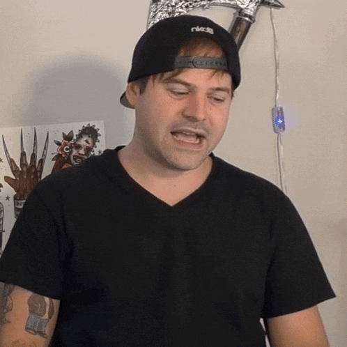 a man wearing a black t-shirt and a black hat with the word ricci on it