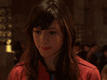 a woman wearing a red jacket looks down at something