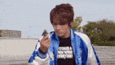 a young man wearing a blue jacket and a black shirt that says your pen win everyday