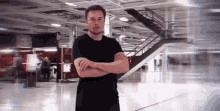 elon musk is standing with his arms crossed in a large room .