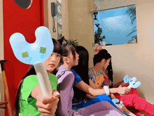 a girl in a green shirt is holding a blue stick with a green leaf on it