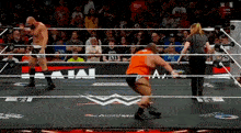 two wrestlers are in a wrestling ring with a referee standing in the middle