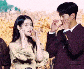 a man in a suit and a woman in a off the shoulder dress are making a heart shape with their hands