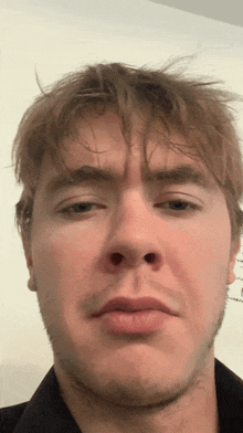 a close up of a man 's face in front of a white board
