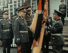 a group of men in military uniforms stand in front of a flag that says e on it