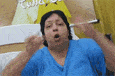 a woman in a blue shirt is sitting in a hospital bed making a funny face