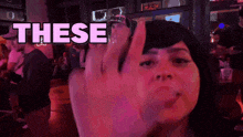 a woman is giving the middle finger in front of a sign that says these