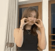 a woman in a black tank top and necklace is making a face .