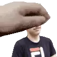 a man in a fila shirt is being slapped in the face by a hand .