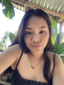 a woman wearing a black top and a gold necklace with a star on it looks at the camera