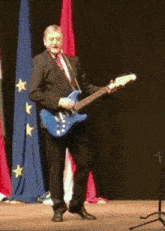 a man in a suit and tie is playing a guitar