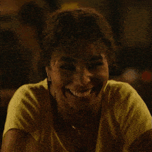 a woman wearing a yellow shirt and necklace smiles