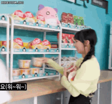 a woman is standing in front of a shelf full of food .