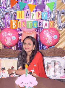 a woman sits in front of a happy birthday banner