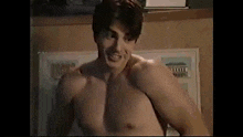 a shirtless man is flexing his muscles in a room .