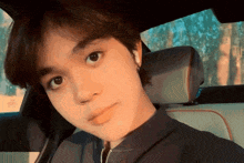 a young man is sitting in the back seat of a car looking at the camera
