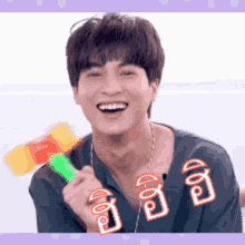 a young man is smiling while holding a water gun in his hand .