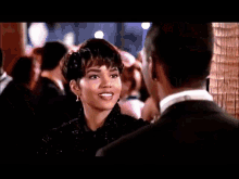 a man in a tuxedo and bow tie is dancing with a woman in a black dress at a party .