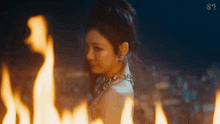 a close up of a woman standing in front of a fire .