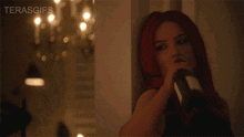 a woman is holding a bottle of wine in front of a chandelier and the words terasgifs are on the bottom