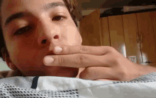 a young man with a tattoo on his forehead is laying on a bed with his hand to his mouth