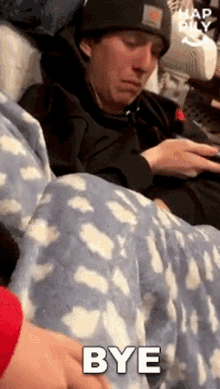 a man is laying in a bed with a blanket and a cell phone .