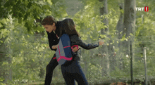 a man and a woman are fighting in front of a trt 1 logo