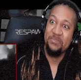 a man with dreadlocks wearing headphones is sitting in a respaw chair .