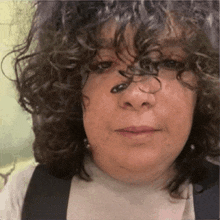 a woman with curly hair looks at the camera with a serious look on her face
