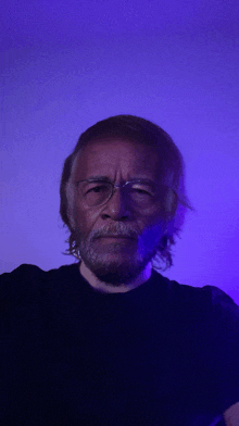 a man wearing glasses and a black shirt looks at the camera