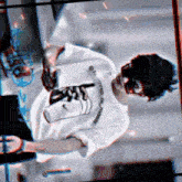 a man wearing a mask and a white t-shirt is standing in front of a laptop .