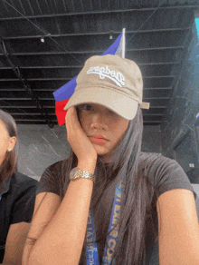 a woman wearing a los angeles hat holds her hand to her chin
