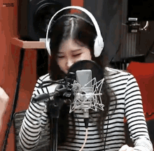 a woman wearing headphones is sitting in front of a microphone in a recording studio .