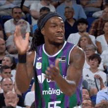 a basketball player wearing a purple and green jersey with the number 55