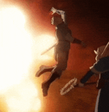 a man is jumping in the air with a sword in his hand while another man stands behind him .