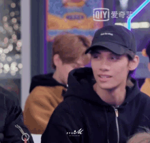 a man wearing a black hoodie and a black hat with the letters zygm on the bottom