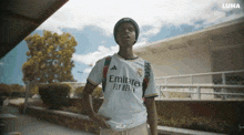 a man wearing a white shirt that says emirates fly better on it
