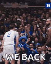 a basketball player with the number 2 on his jersey is standing in front of a crowd of people .
