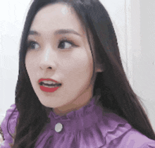 a close up of a woman 's face wearing a purple top and red lipstick